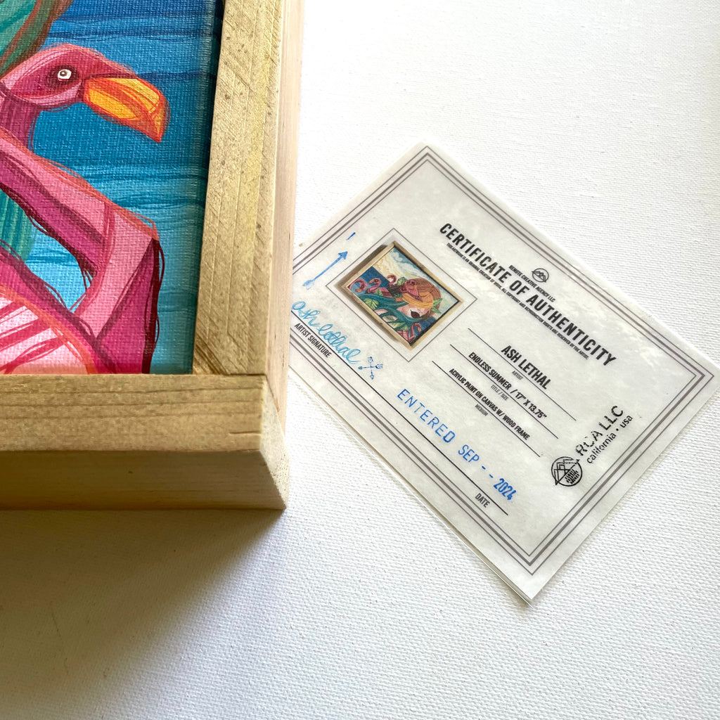 Framed artwork of a flamingo with a certificate of authenticity on a white surface