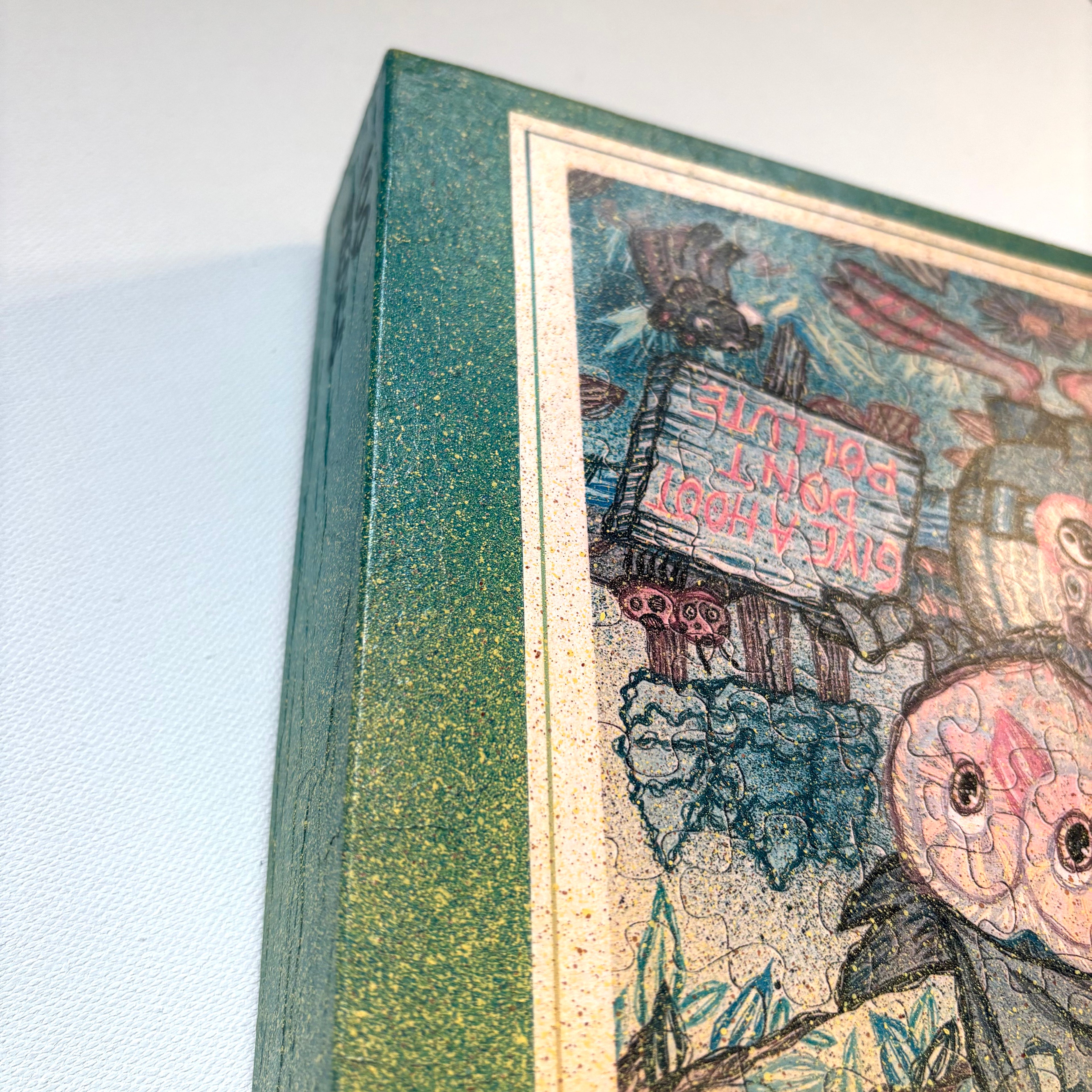 Close-up of a painted puzzle box with a colorful illustration on the cover, featuring a owl character with a sign.
