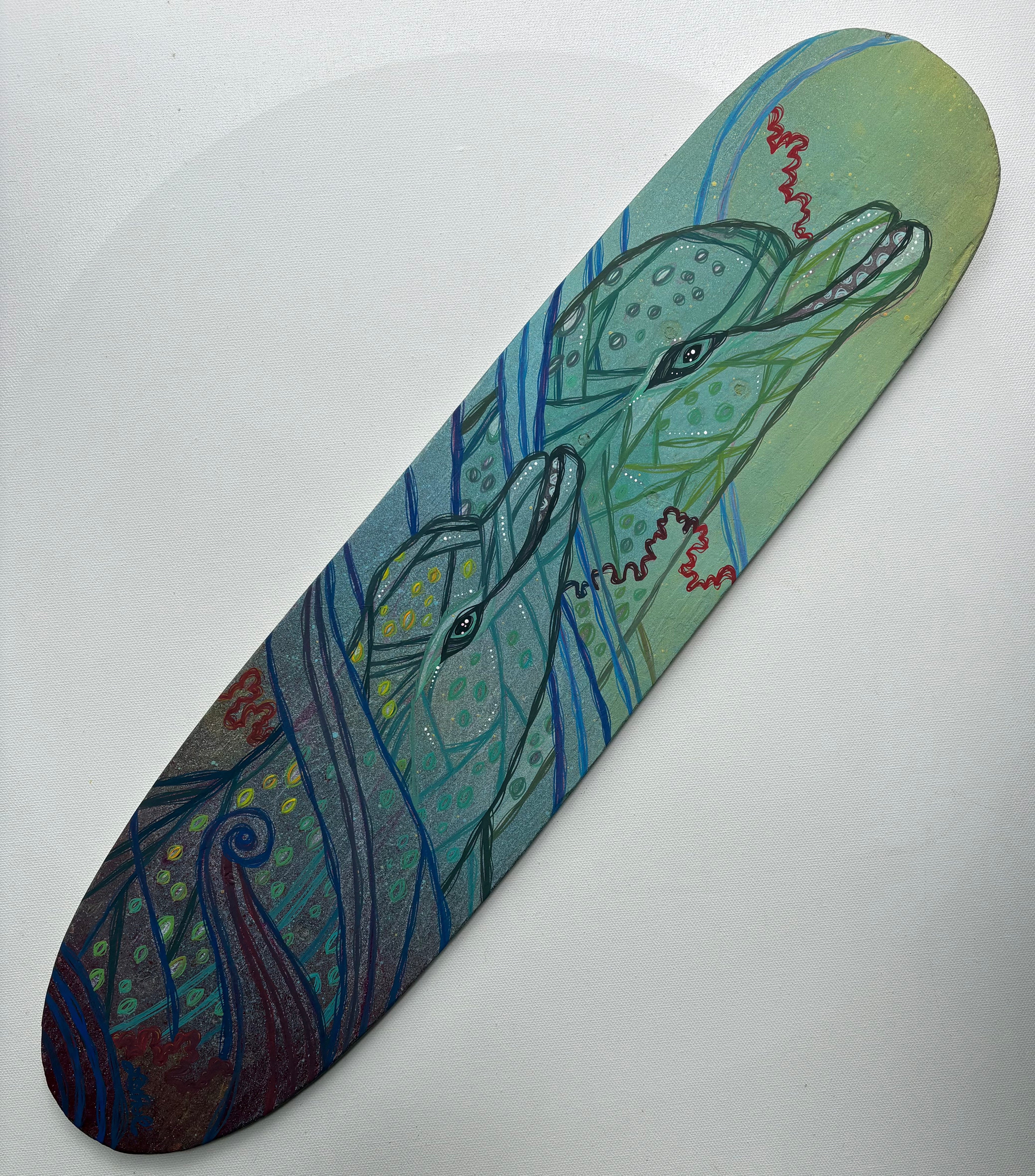 Skateboard deck with a colorful dolphins design on a white background