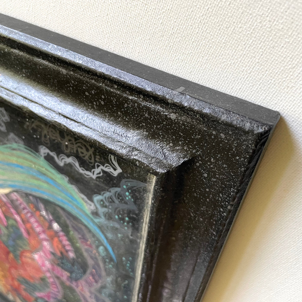 Close-up of a textured black frame corner with a colorful painting inside.