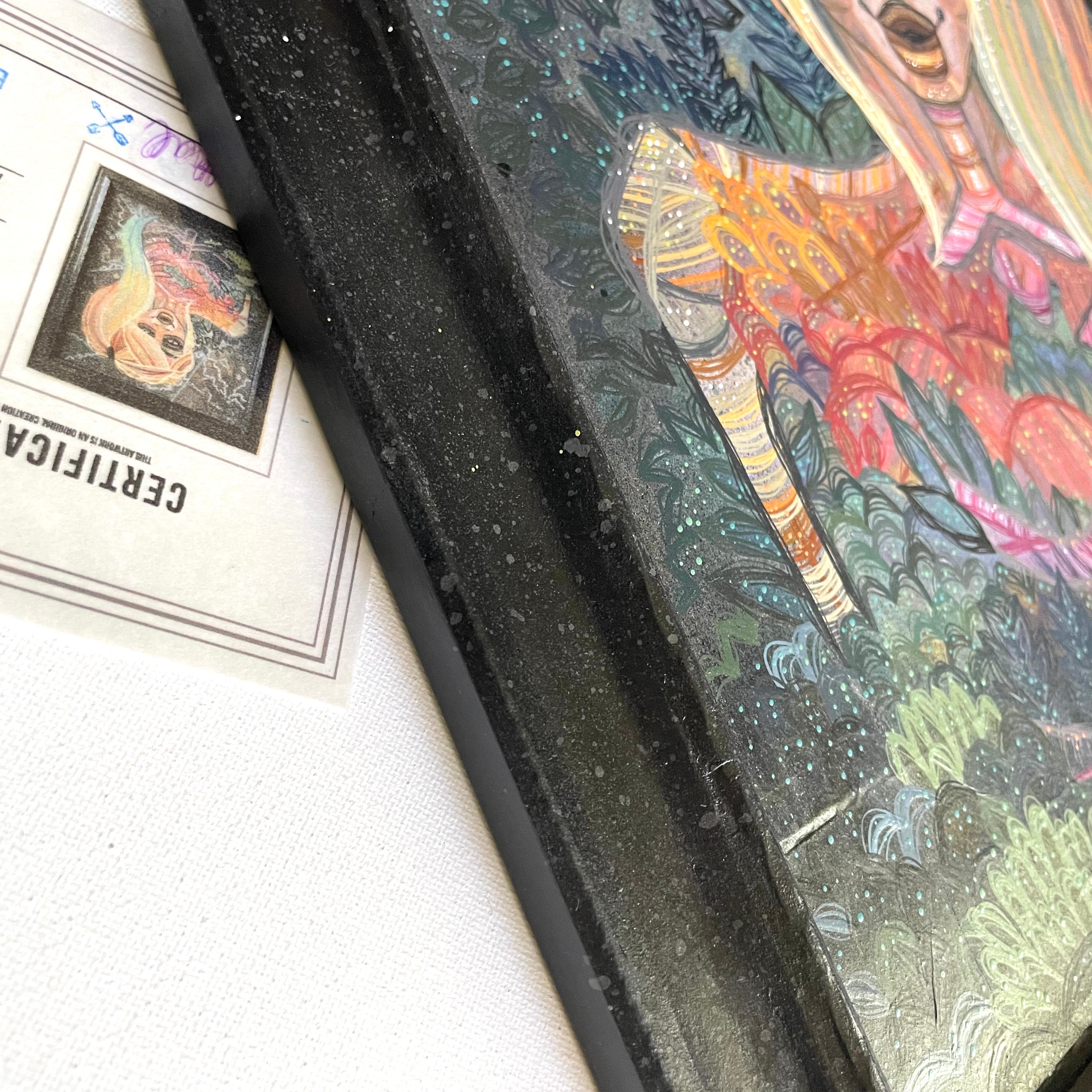 Colorful abstract feminine energy space painting with a black frame on a white surface
