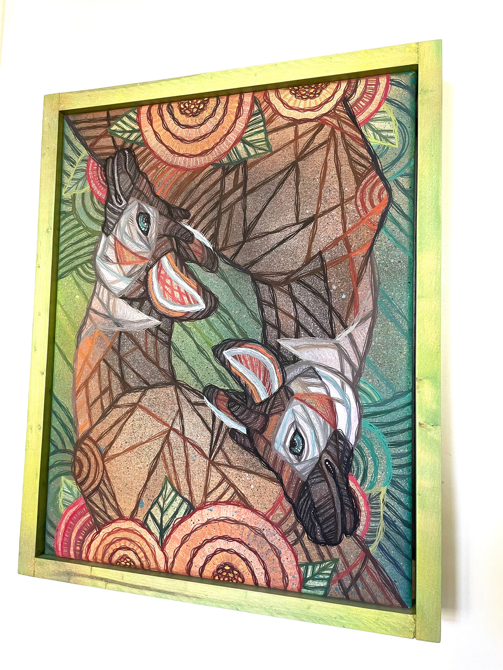 Framed artwork of two okapis in a geometric, abstract style with a custom wood stained frame