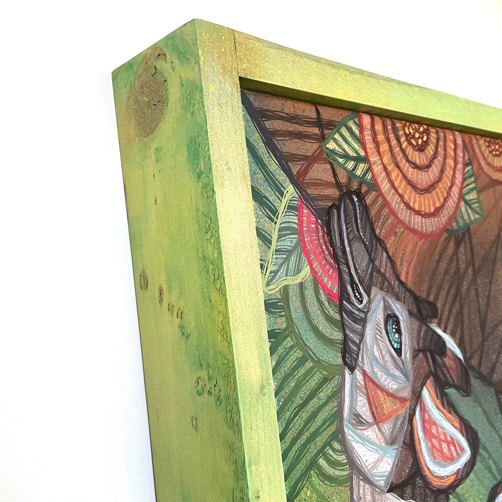 Close-up of a wood framed painting with a colorful abstract design on a white gallery wall 