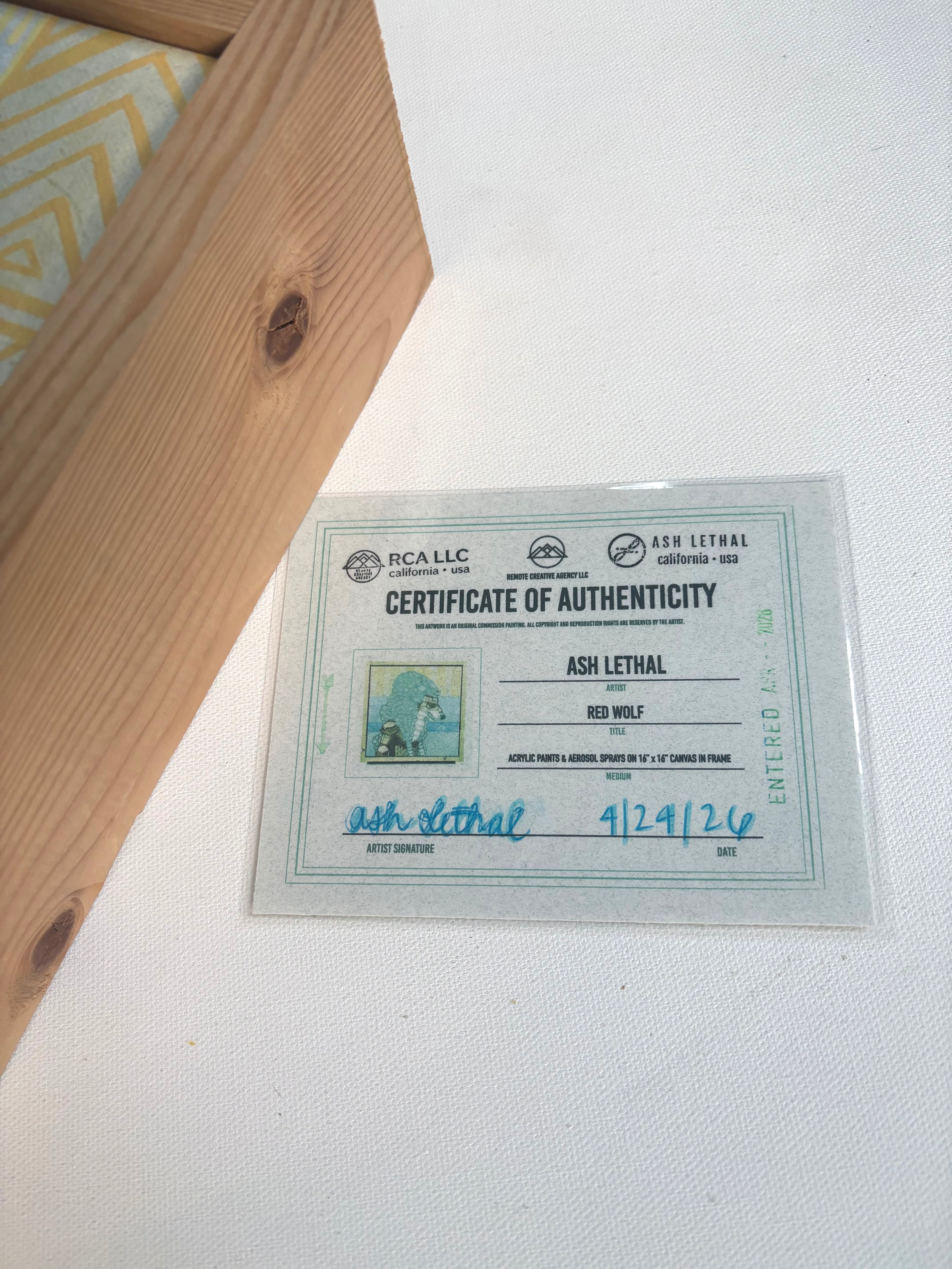 Certificate of Authenticity for 'Red Wolf' by Ash Lethal on a white surface with wooden frame.