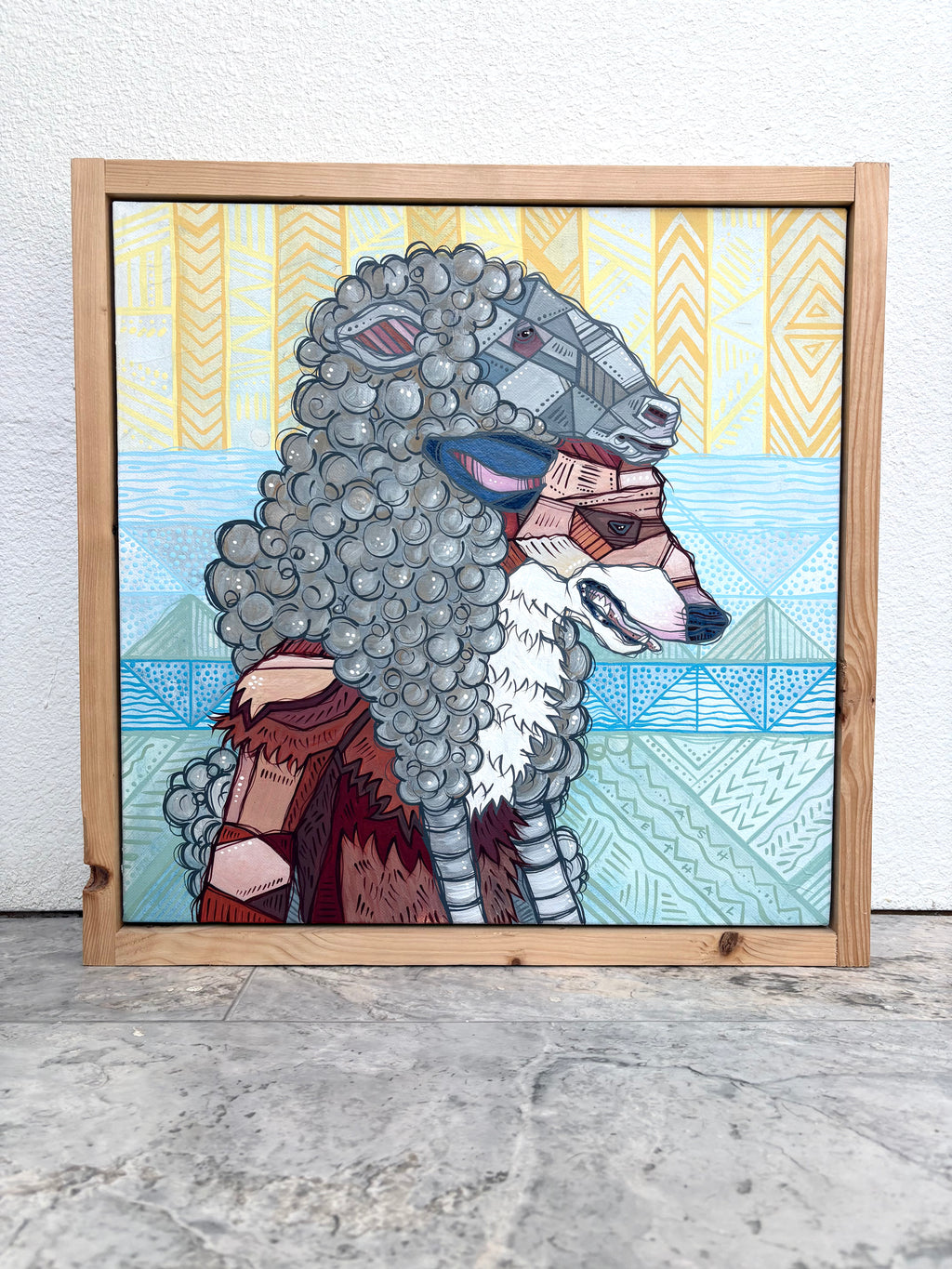 Framed artwork of a stylized wolf and sheep with geometric patterns on a textured surface.