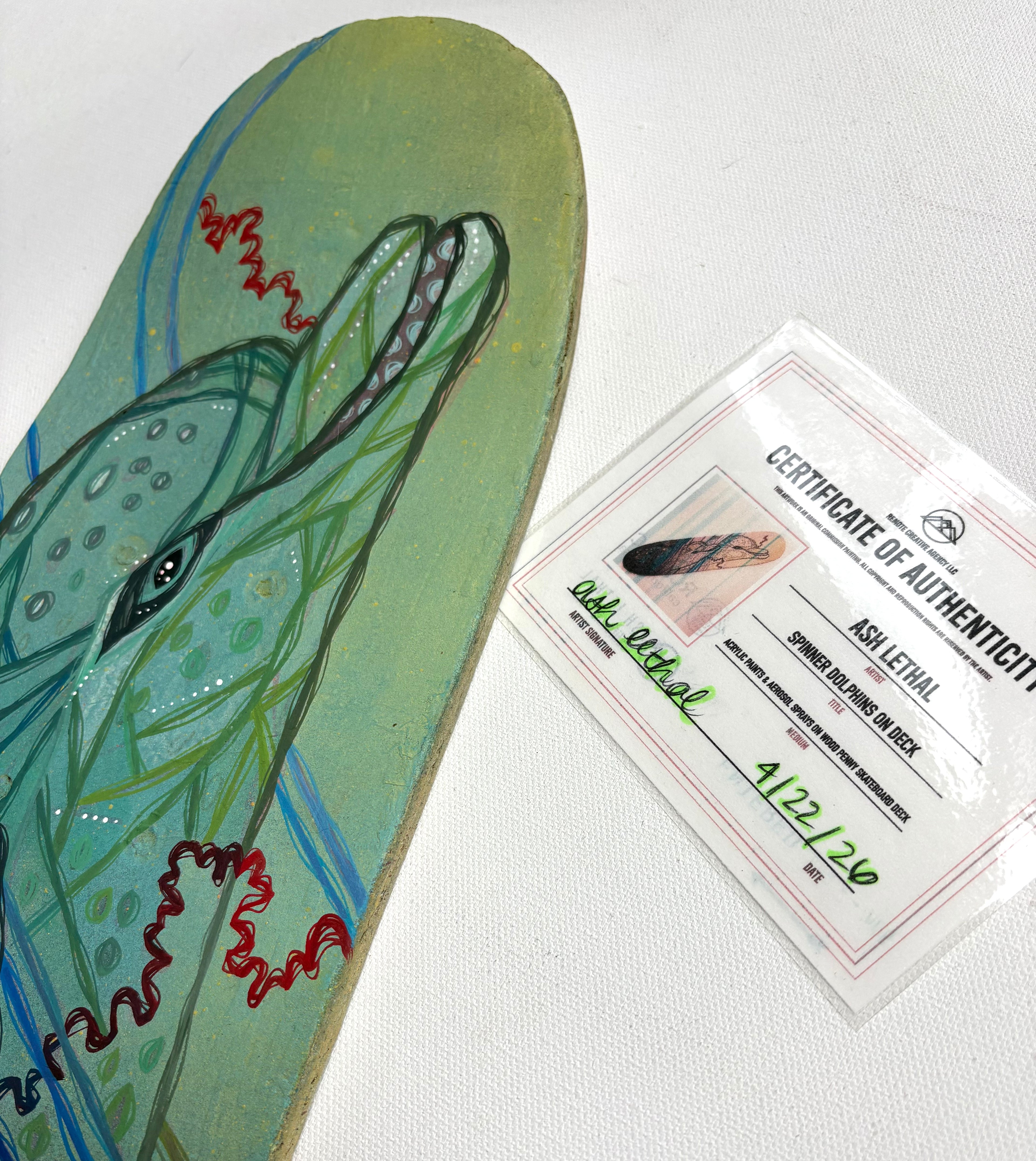 Skateboard deck with a hand-painted spinner dolphin wildlife design and a certificate of authenticity on a white background