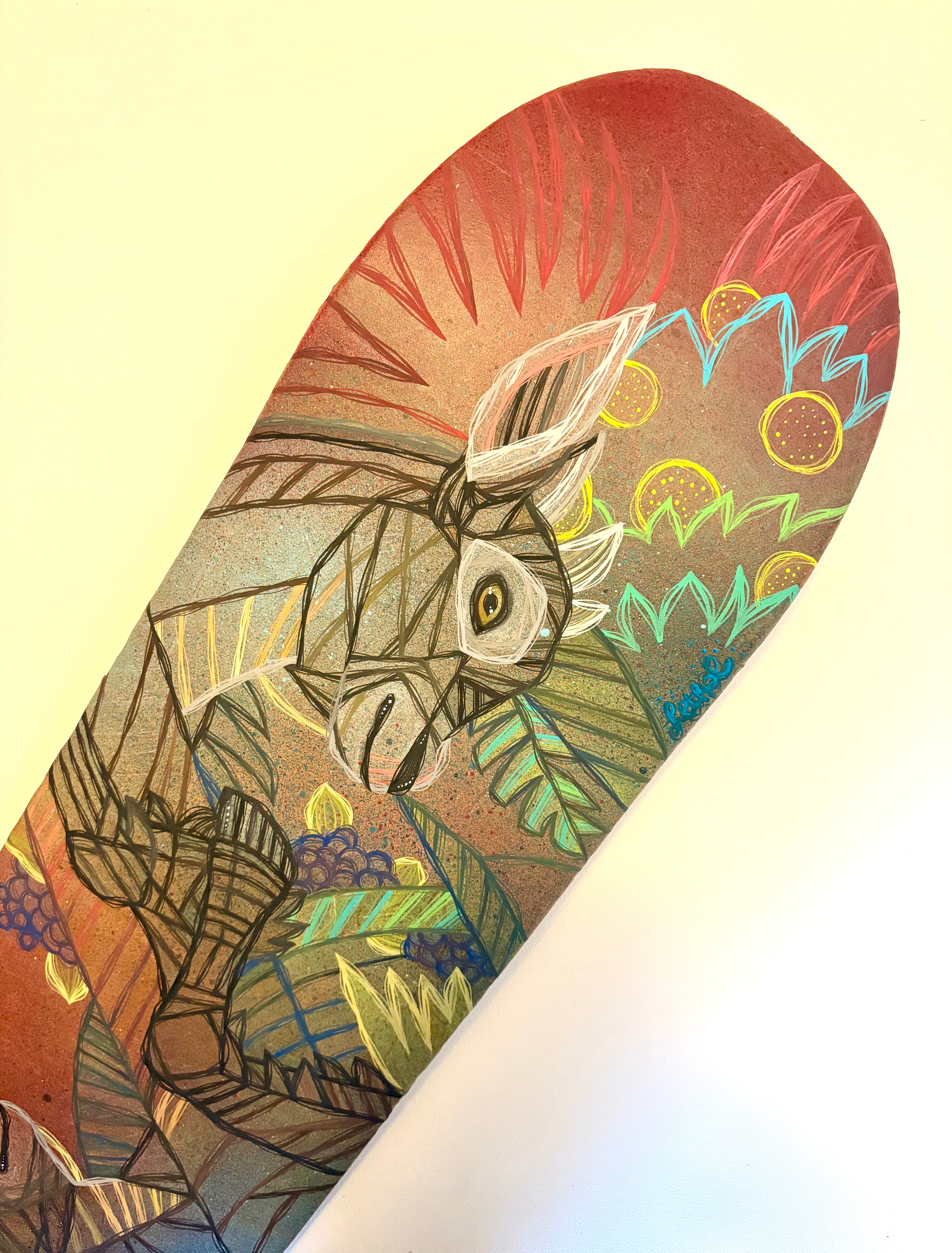 Skateboard deck with a colorful design of a goat in a natural setting with fruits and plants by ash lethal