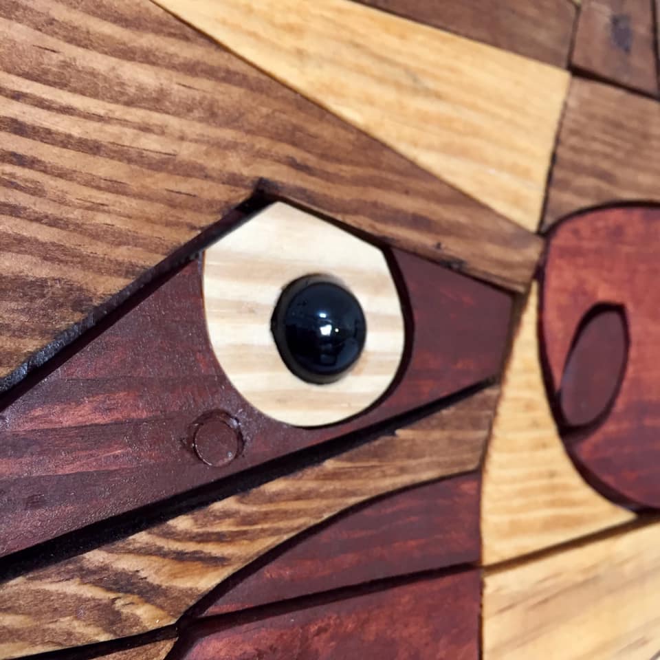 Wooden puzzle piece with a black eye on a wooden surface