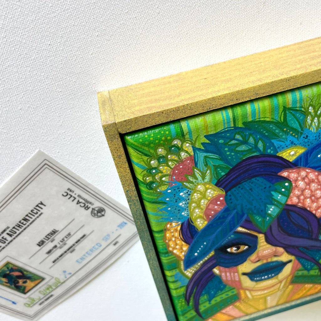 Colorful artwork of a face with a blue mask and decorative elements, accompanied by an authenticity certificate.